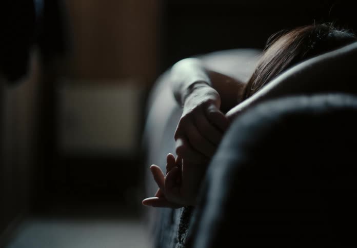 Woman with brown hair lies on bed thinking