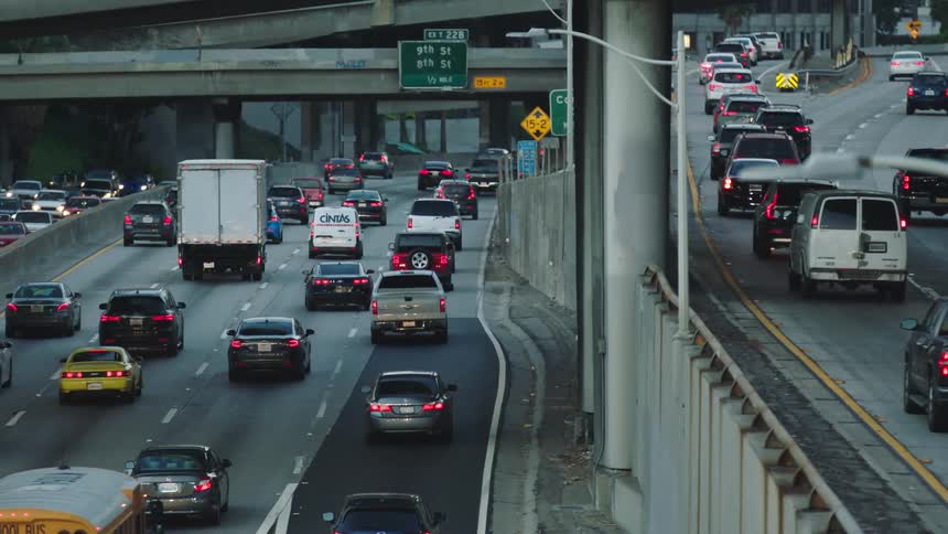Vehicles driving down a freeway in a busy city