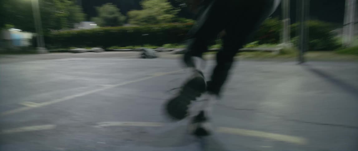 A man is doing layups on the basketball court at night
