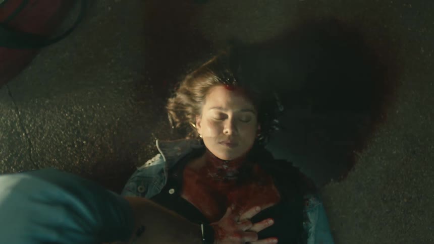 An emt continues chest compressions on a bloody injured woman in the street