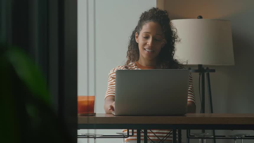 A woman is typing on a laptop and sitting at a table