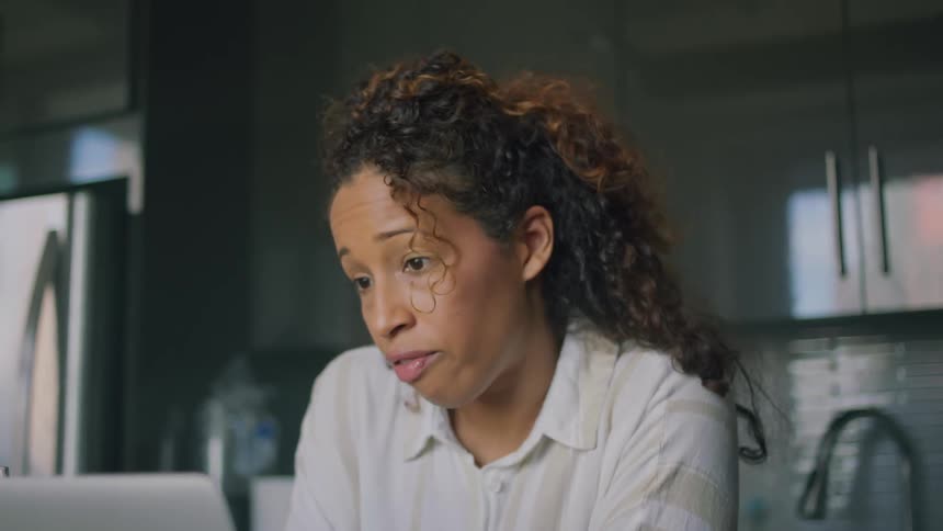 A woman is video chatting in the kitchen with someone