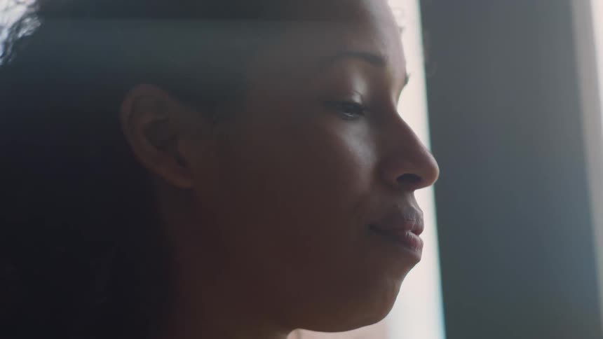 A woman is typing on a laptop next to a window
