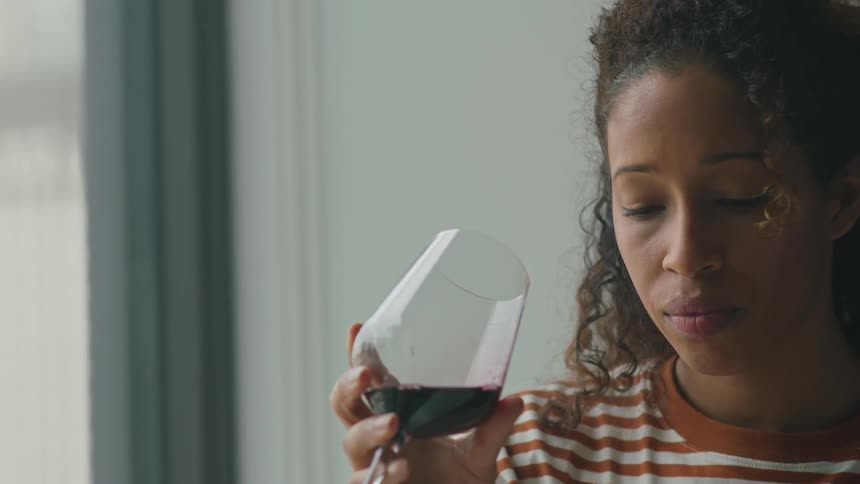 Woman sits and read a hardback book while drinking wine