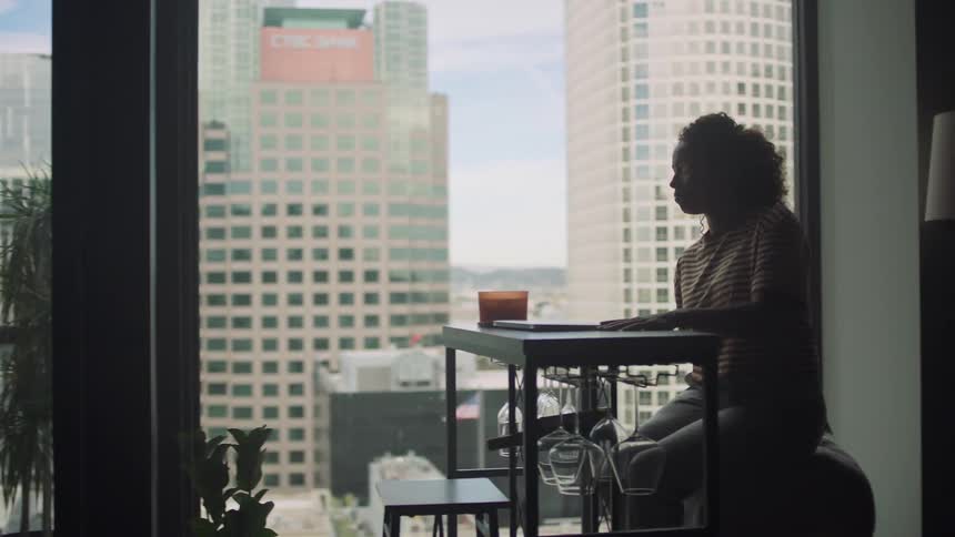 A woman is sitting at a table with her laptop in a city