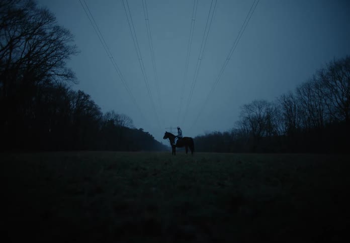 A young woman is sitting on a horse between two hills