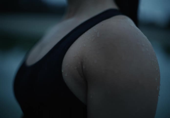 Sweat drips down the upper arm of a female athlete while training outside