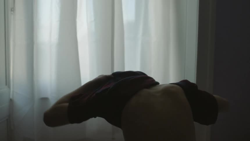 A boy is sitting in his room facing a window