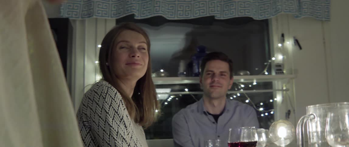 People are sitting at a dining room table listening to someone