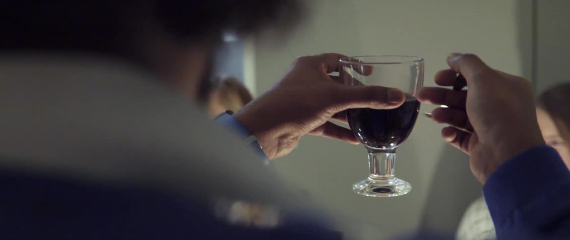 A man taps a glass full of wine as if he wants to make a toast