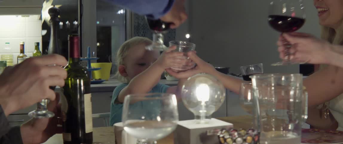 Happy family and young child celebrating with a toast at a festive dinner party.