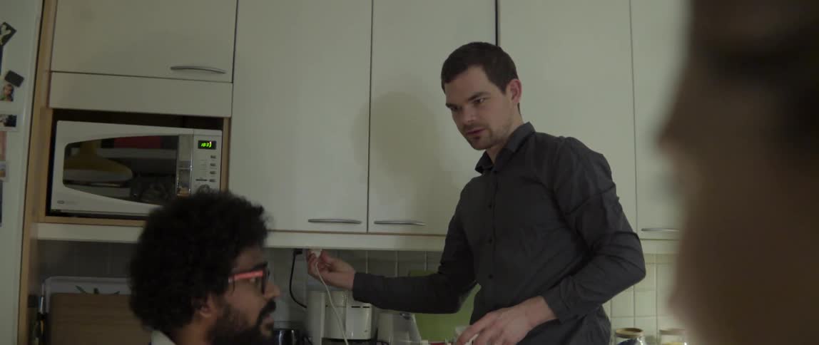 Two Men Talking in a Small Kitchen With Warm Conversation and Comfortable Casual Vibe
