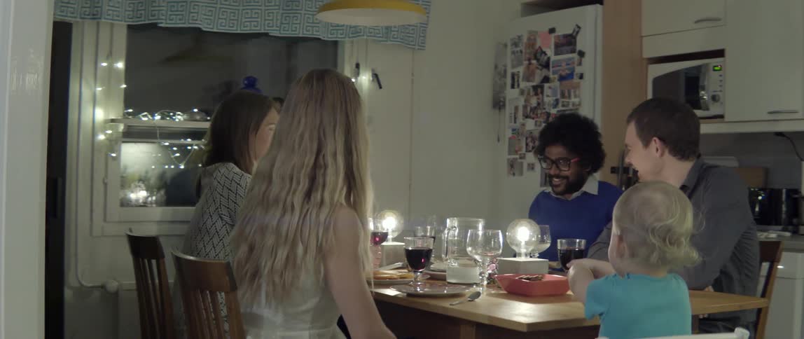 Wide shot of family and friends enjoying deep conversation during a social dinner gathering.