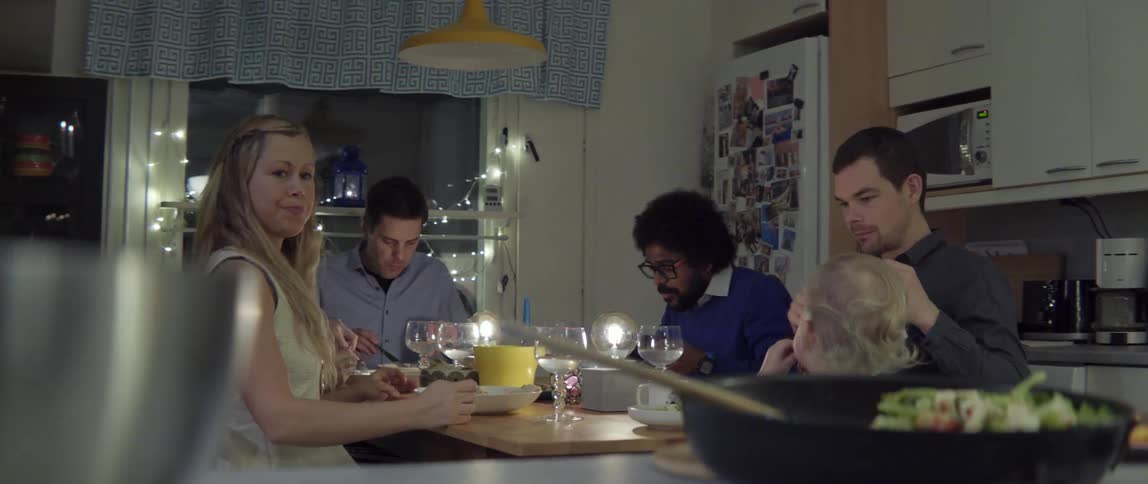 Close up of happy friends eating and laughing together at a cozy dinner table.