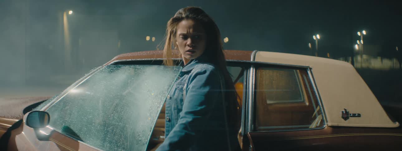 A woman goes to get in her car and then nervously looks behind her