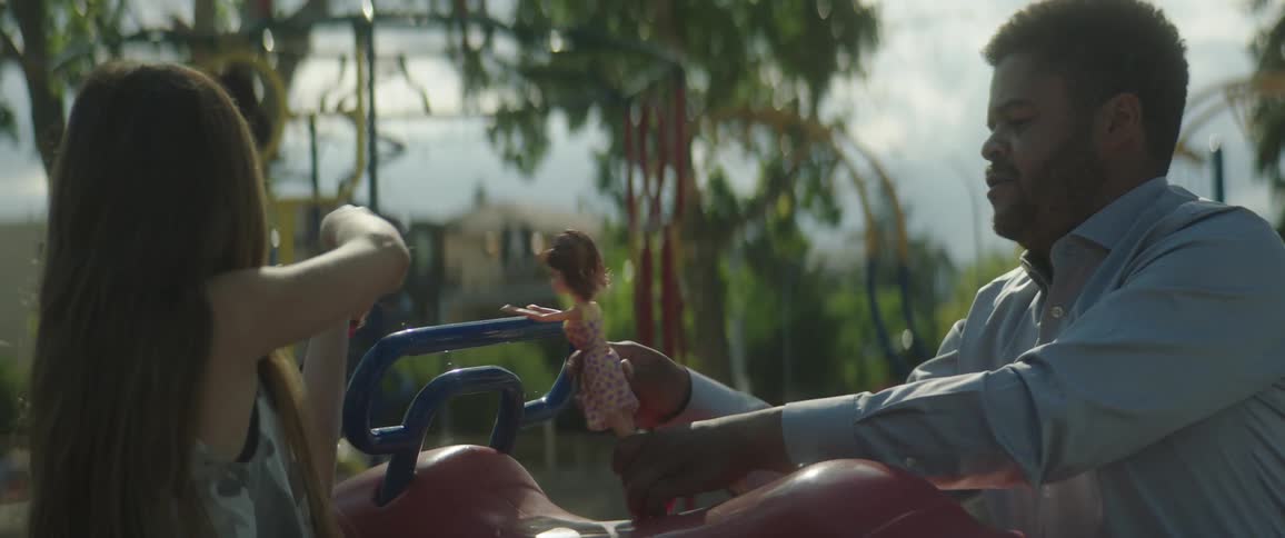 Dad plays with his daughter making barbie dolls do gymnastics at the playground