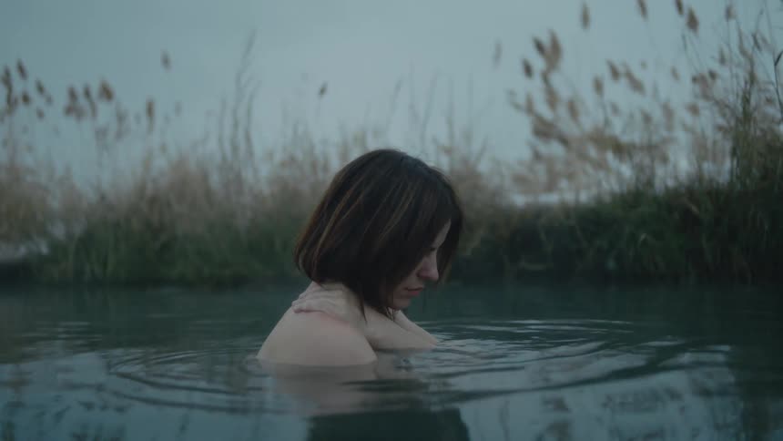 Woman smiles as she soaks in water outdoors