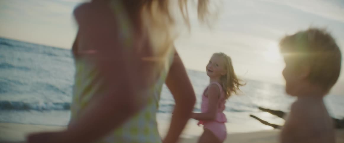 Three children run into the ocean