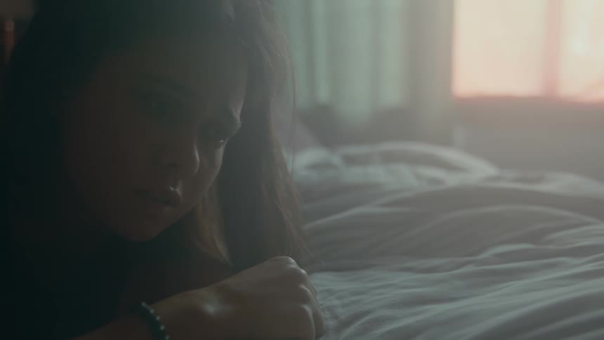A sad looking teenage girl lies in bed