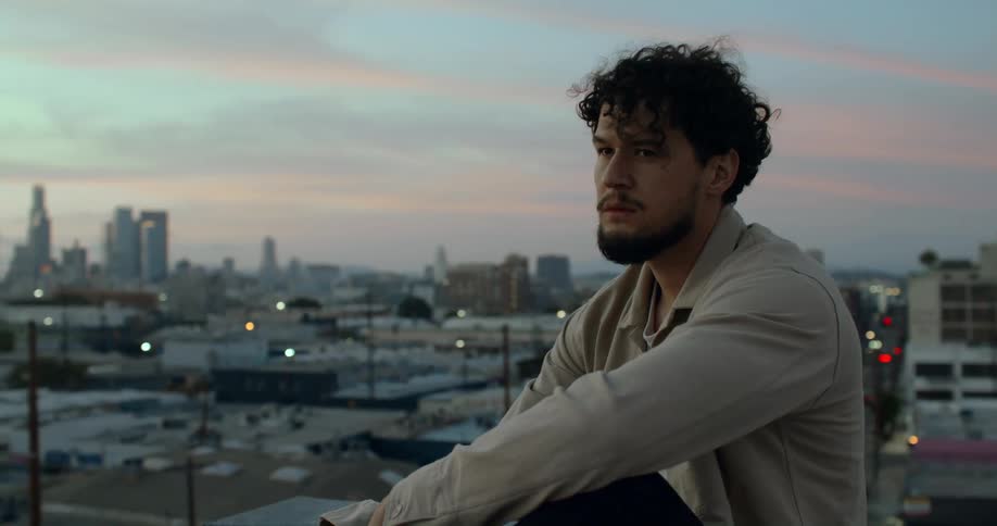 A man sits on top of rooftop near downtown
