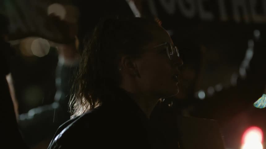 Protesters call and hold signs at rally at night