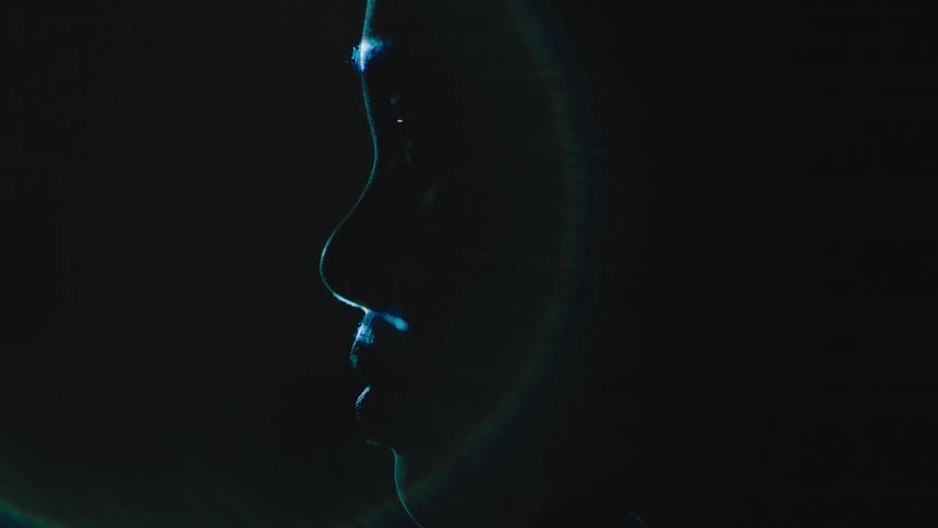 Glare from projector casting images across a persons face in the dark