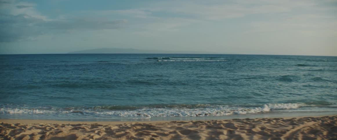 Waves are rolling into shore and over the sand on the beach