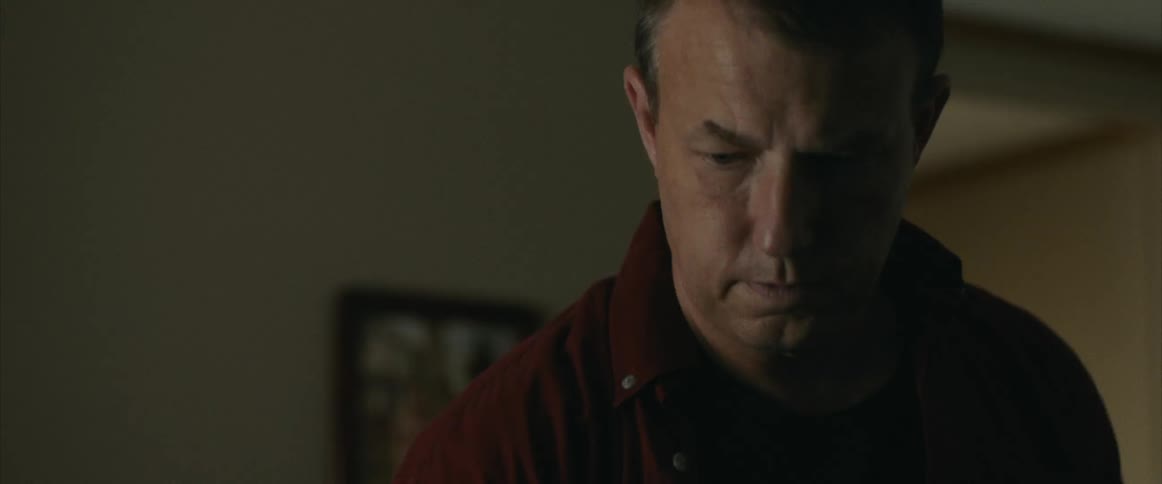 An angry looking man turns and walks out of a room in a house