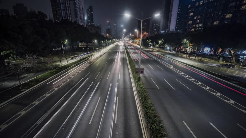 Traffic travels along a large street through a metropolis at night