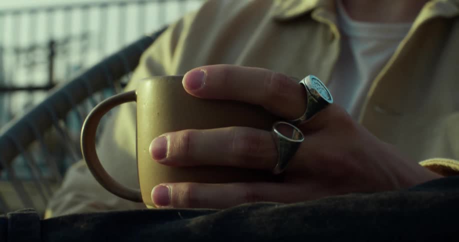 A person is holding a cup of coffee while sitting down outside