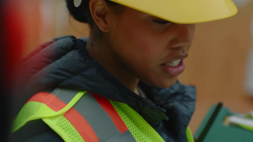 A woman on a construction site talks with an employee