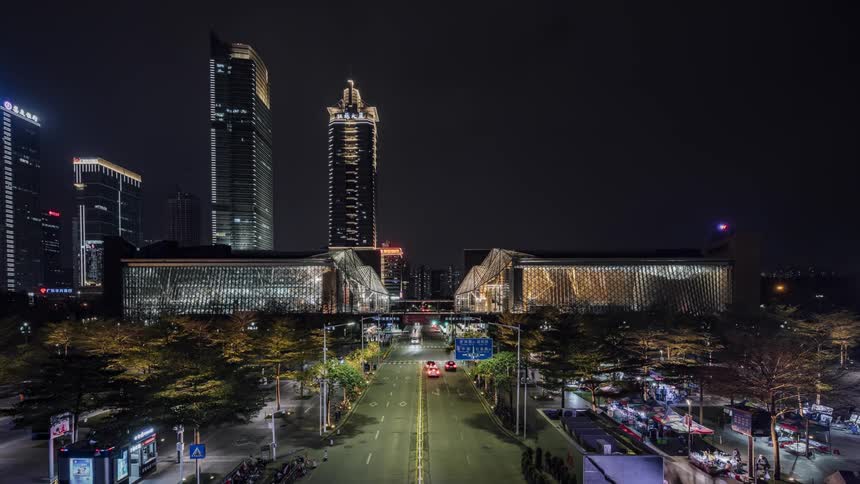 People hang out downtown as traffic passes by at night