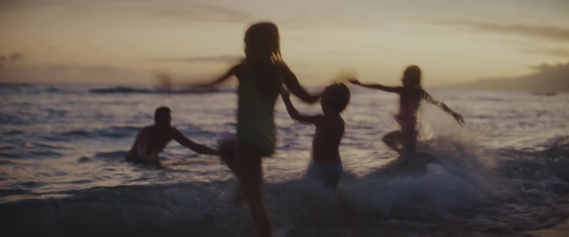 Father and his three children playing around and having fun on an empty beach at dusk