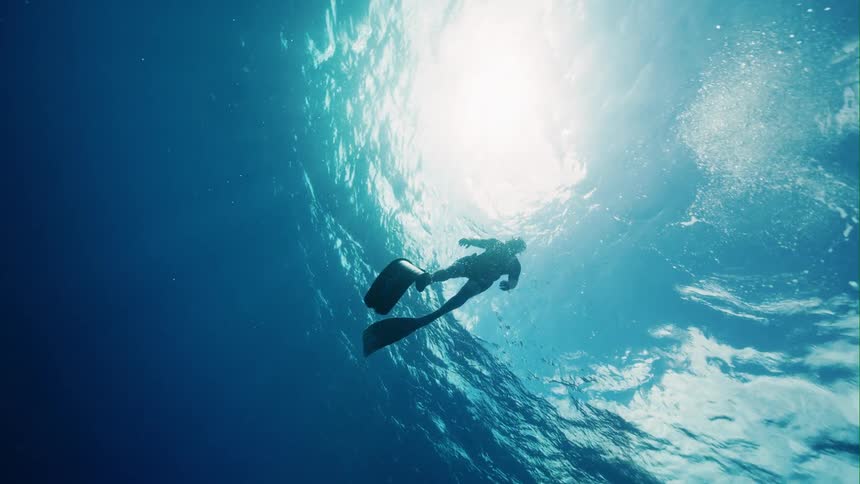 A man is swimming under the ocean water