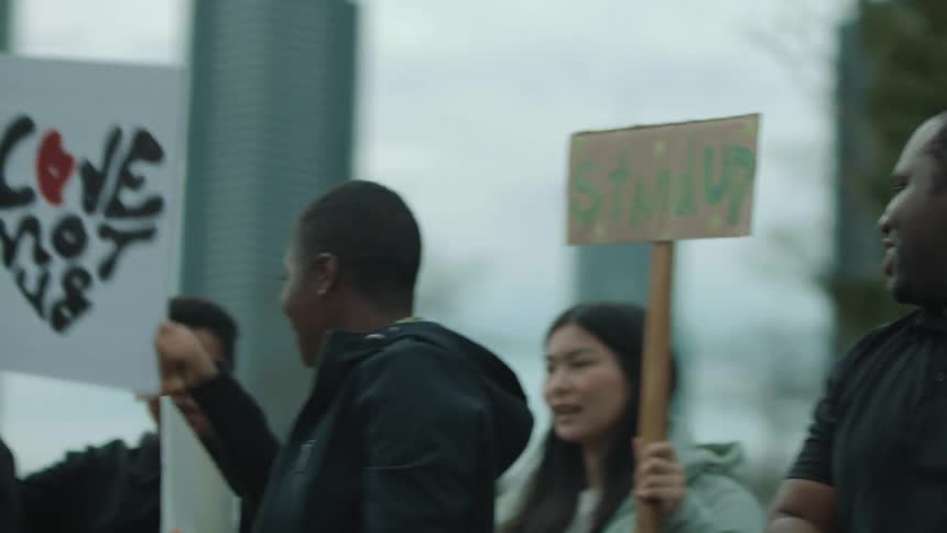 People holding signs at a rally talk and high five and hug one another