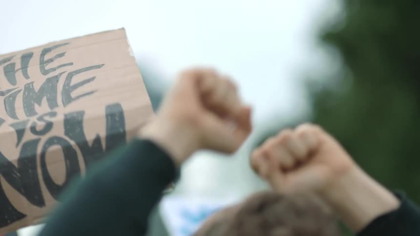 Small protest crowd holding protest signs at a public space in a big city