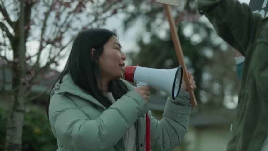 A woman leads a group of people in a protest in a neighborhood