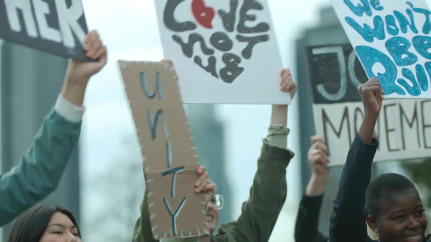 People hold signs in the air at a rally