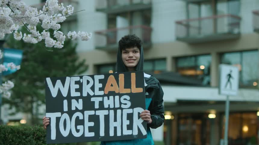 A man smiles while holding a sign