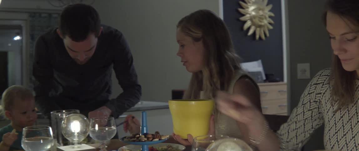 People passing around food at dining table with warm communal energy