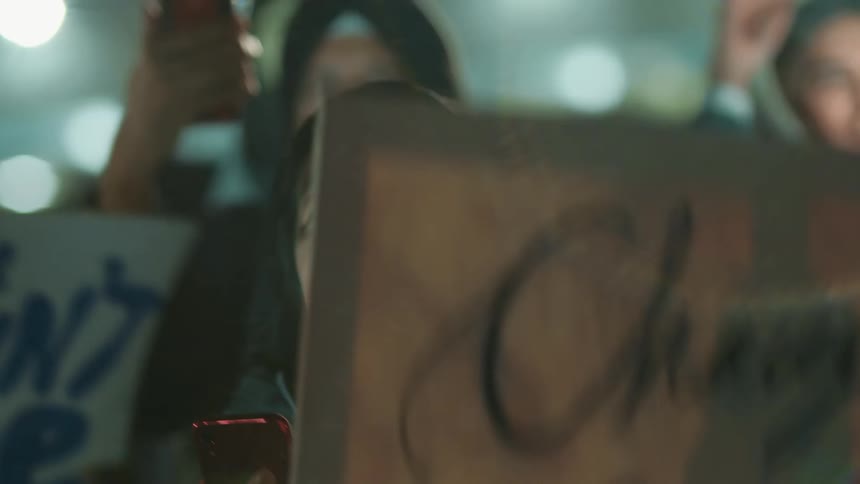 A woman protests with a sign and records with her smartphone