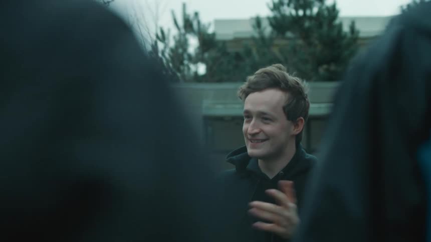 Man smiles whiles standing with a group of people talking