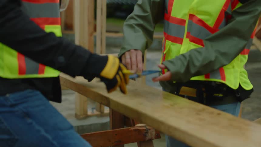 A female construction worker helps another employee at the site