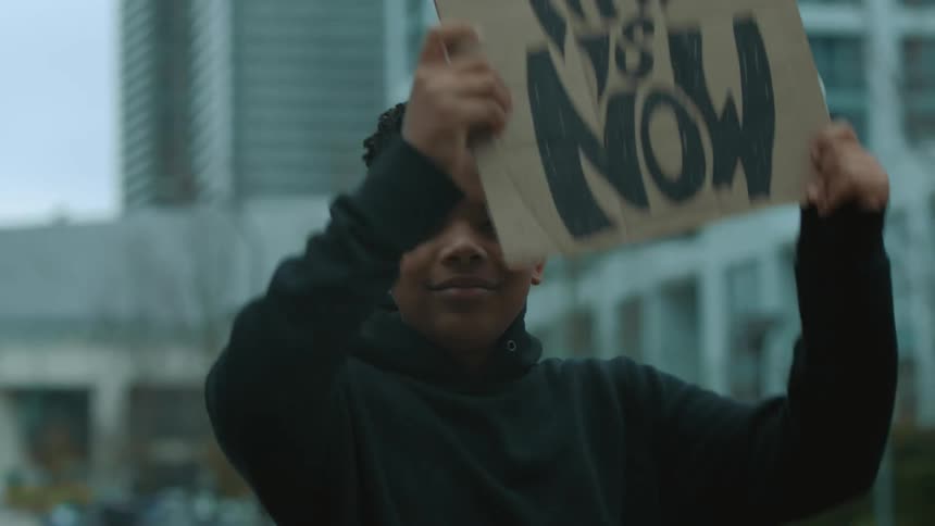 A teenager lifts the sign above his head
