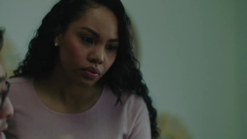 A female walks around an office table to check on her coworkers