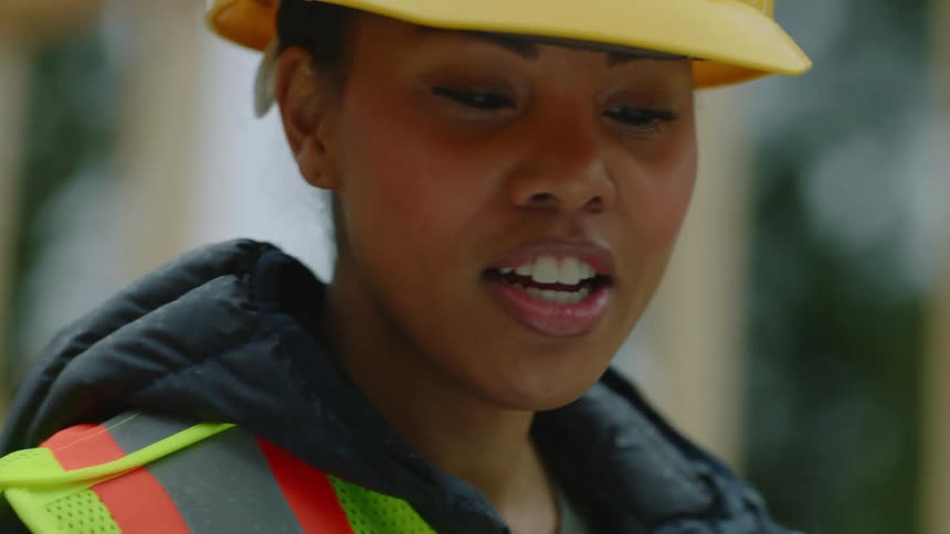 Two women look at a blueprint on a construction site