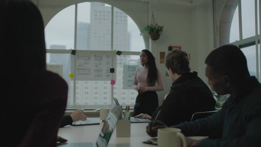 Colleagues take notes and ask questions during a team meeting