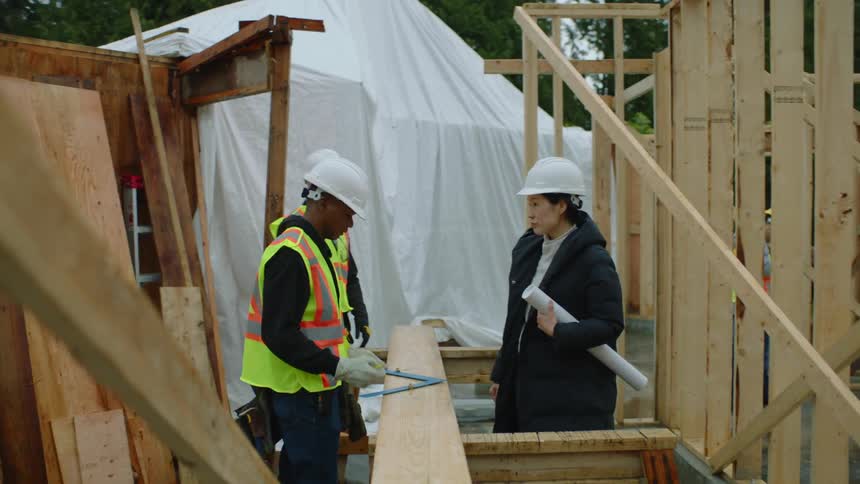 Construction workers gather at a building frame talking together