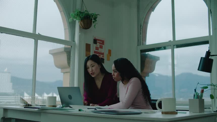 Two women look at a laptop in the office