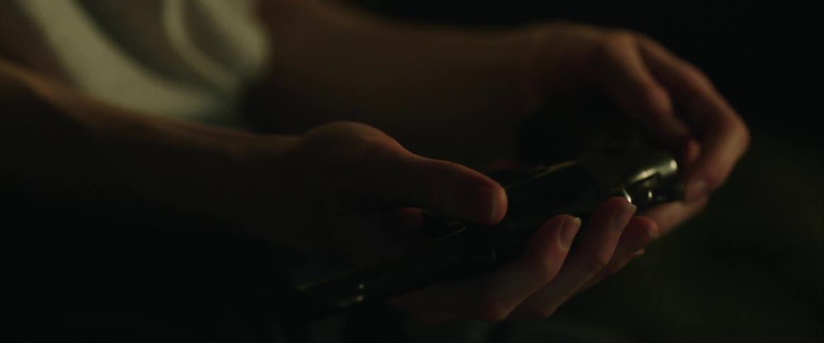 A person moves a gun around in their hands in the dark